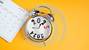 Close-up of calendar and clock alarm clock on yellow background with copy space. Transition from 2023 to 2024, Business startup