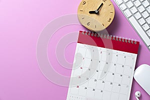 close up of calendar keyboard computer and alarm clock on the pink table background planning for business meeting or trave