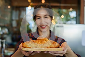 Close-up camera in front bakery owner handing out tray with small croissants, slowly backed away at reasonable distance, woman