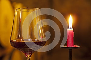 Close-up of a candle and a glass with red wine in a wine cellar