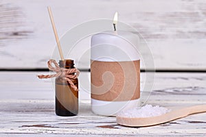 Close-up candle with oil bottle and spoon with salt.