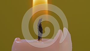 Close-up of candle wick ignited with match isolated on yellow background