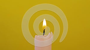 Close-up of candle wick ignited with splinter isolated on yellow background