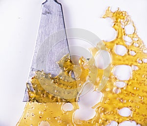 Close up of cannabis oil concentrate aka shatter isolated against white background