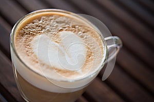 Close up of cappuccino cup with heart shaped milk pattern at cafe. a cup of coffee art.