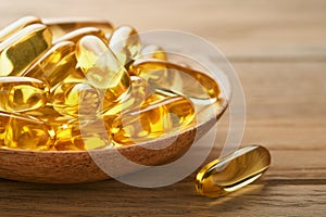 Close up capsules with Vitamin D, E or Omega 3,6,9 fatty acids in bottle on old wooden backgrounds. Food supplement oil filled