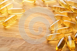 Close up capsules with Vitamin D, E or Omega 3,6,9 fatty acids in bottle on old wooden backgrounds. Food supplement oil filled