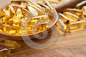 Close up capsules with Vitamin D, E or Omega 3,6,9 fatty acids in bottle on old wooden backgrounds. Food supplement oil filled