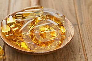 Close up capsules with Vitamin D, E or Omega 3,6,9 fatty acids in bottle on old wooden backgrounds. Food supplement oil filled