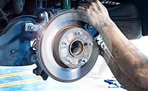 Close up car disk brake pad replacement service  with hand of mechanic man in car garage and copy space, use for disk brake