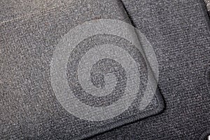 Close-up on a car floor mat in the back of a minivan made of black carpet on a white isolated background. Auto service industry.
