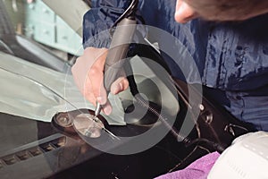 Close up Car glaze worker fixing and repairing a windshield or windshield of a car at a garage service station. Drill