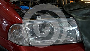 Close up car headlight with opened hood.