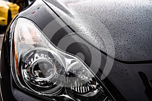 Close-up of Car Headlights with Raindrops on Hood