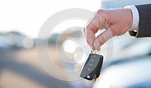 Close-up of car keys and car papers in front of new cars at a car dealership