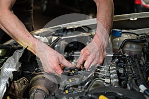 Close up of car mechanic hands removing fuel injectors.