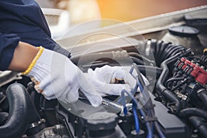 Close up Car Mechanic man hands repairing car auto repair shop. Man hands fixing machinery vehicle mechanical service. open