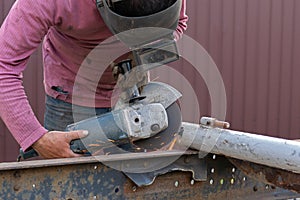 A close-up of a car mechanic using a metal grinder to cut a car bearing in an auto repair shop