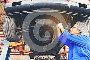 Close-up of car mechanic working under car in auto repair service.