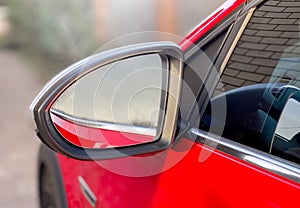 Close-up car mirror for viewing the blind spots of a red car. Car details