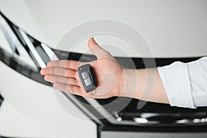 Close up of the car owner& x27;s hand holding the delivery key to buyers. Concept of selling cars and giving keys to new