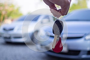 Close up of the car owner`s hand holding the delivery key to buyers. Concept of selling cars and giving keys to new owners