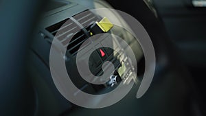 Close-up car panel with male finger pressing red triangle car hazard warning button. Unrecognizable Caucasian man in