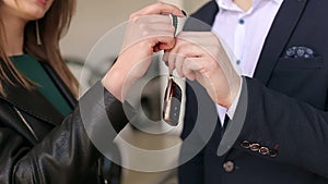 Close-up of the car salesman gives the girl the keys to the new car.