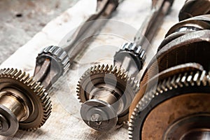 Close-up on a car shaft with gears and bearings removed for replacement on a workbench in a repair shop for vehicles. Auto service