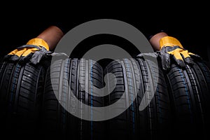 Close up of a car tire with yellow rubber gloves and black background.