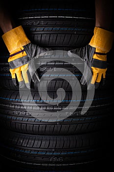 Close up of car tires and hand with gloves on black background. Concept of car service.