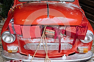 Close up car trunk full of Christmas gifts of retro red car in magic New Year decorated exterior with festive lights