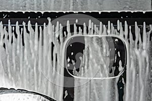 Car wash with soap. Black car covered by foam