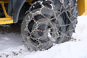 Close-up of a car wheel in iron chains on the snow, winter travel safety concept with snow chains on tire