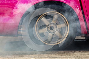 Close up car wheel with smoke on the asphalt road speed track, Car wheel drifting and smoking on track, Car wheel spinning