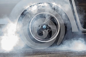 Close up car wheel with smoke on the asphalt road speed track, Car wheel drifting and smoking on track, Car wheel spinning