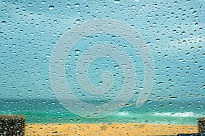 Close up of car windshield with raindrops and sandy beach