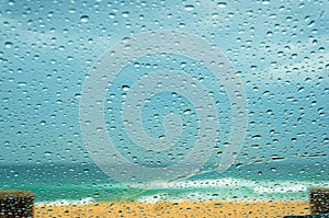 Close up of car windshield with raindrops and sandy beach