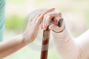 Close-up of caregiver holding hand of a senior person with walki