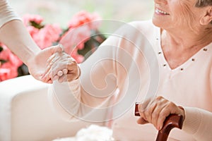 Close-up of caregiver supporting smiling senior woman with walki