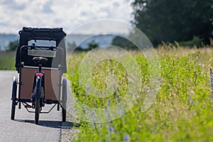 Close-up of a cargo bike parked on rural road near grassy field on sunny day