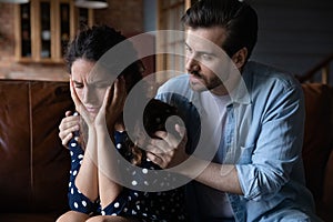 Close up caring man hugging unhappy woman, comforting or apologizing