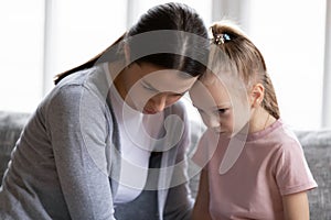 Close up caring young mother calming offended little daughter