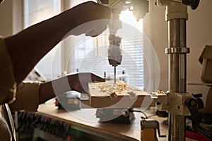 Close Up of Carpenter Drilling Wood Using Machine Tool in Workshop with Sunlight