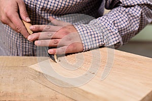 Close up of carpenter hands cutting wooden board with chisel