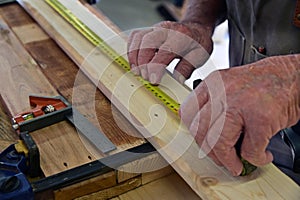 Close up of carpenter hands measuring a wooden plank