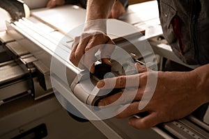 Close up of carpenter hands working with sliding panel saw at furniture factory workshop. Production, manufacture and