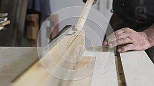 Close-up: a carpenter in his workshop saws a wooden board with a circular saw, makes furniture parts in natural light. A