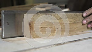 Close-up: a carpenter in his workshop saws a wooden board with a circular saw, makes furniture parts in natural light. A