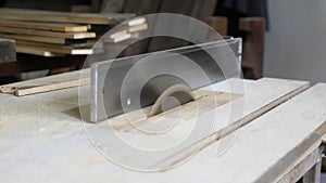 Close-up: a carpenter in his workshop saws a wooden board with a circular saw, makes furniture parts in natural light. A